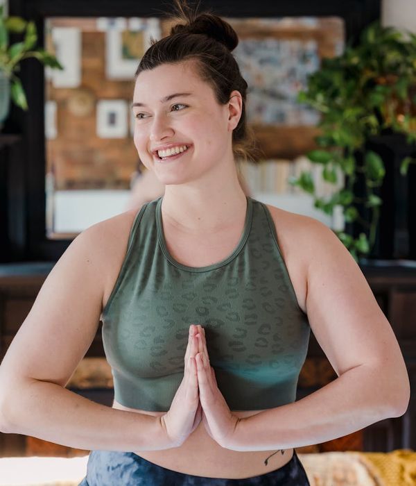 Smiling woman in sportswear feeling balanced and calm in a light room.